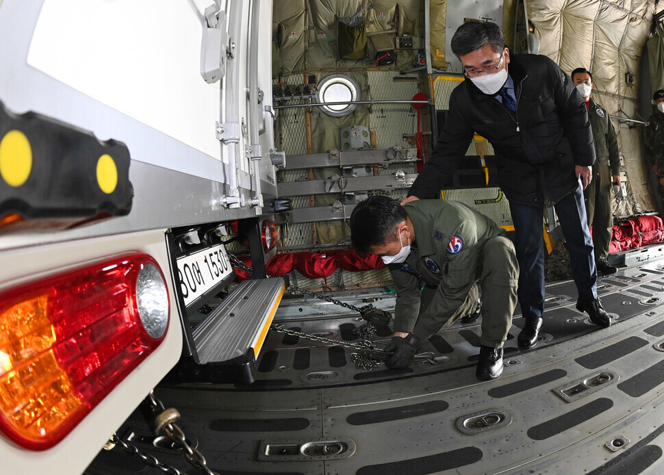 South Korean Minister of National Defense Suh Wook encourages a military staffer who is fixing a COVID-19 transport vehicle on an Air Force transport aircraft during a second round of “pan-governmental integrated simulation” exercises for COVID-19 vaccine distribution held on Feb. 19 at Seoul Air Base in Seongnam. (press photo pool)