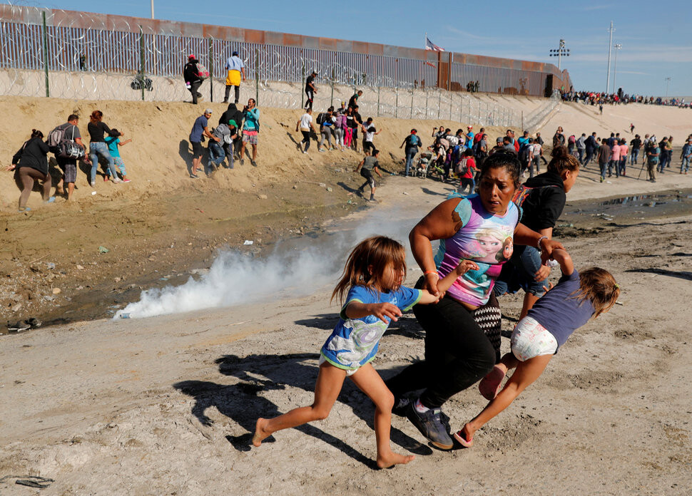지난 11월25일 미국과 국경을 맞댄 멕시코 북부 티후아나에서 최루탄이 터지자, 카라반에 참여했던 온두라스 여성이 5살 쌍둥이 딸의 손을 잡고 황급히 피하고 있다. REUTERS 연합뉴스