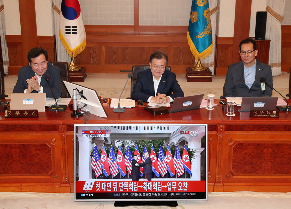 South Korean President Moon Jae-in smiles as he watches a live broadcast of the North Korea-US summit in Singapore at the main pavilion of the Blue House on June 12. On the left is Prime Minister Lee Nak-yeon and on the right is Ko Hyung-kwon