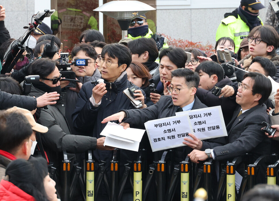 차성안 서울시립대 법학전문대학원 교수(가운데) 등이 13일 오후 서울 용산구 한남동 관저 앞에서 경호처 관계자에게 부당지시거부 소명서를 전달하려고 하고 있다. 연합뉴스
