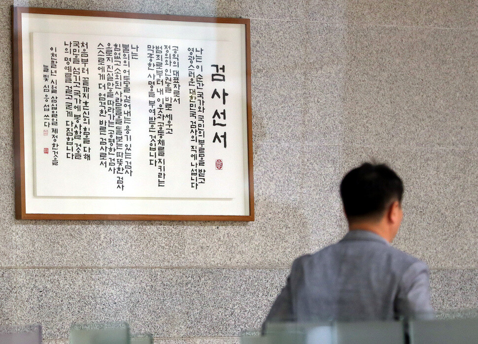 A man passes by a framed copy of the prosecutor’s oath