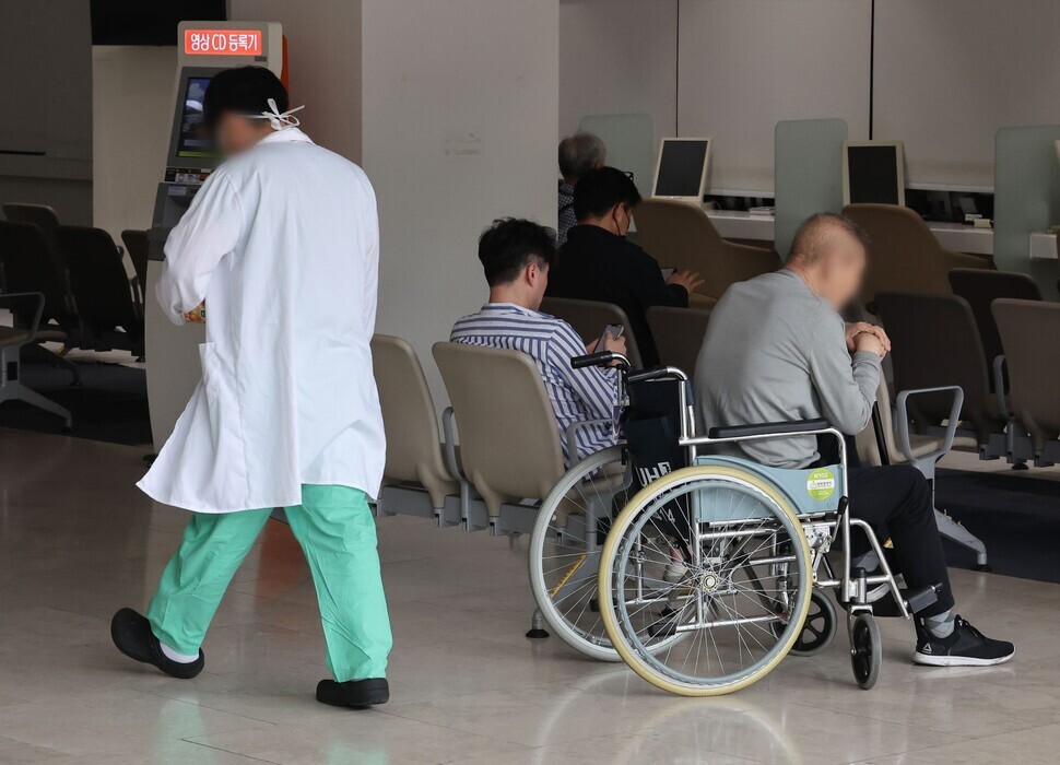 A person in scrubs and a white coat walks through a waiting area at a major hospital in Seoul on June 6, 2024, amid a monthslong clash between the government and physicians groups over a plan to increase medical school admissions in Korea. (Yonhap)