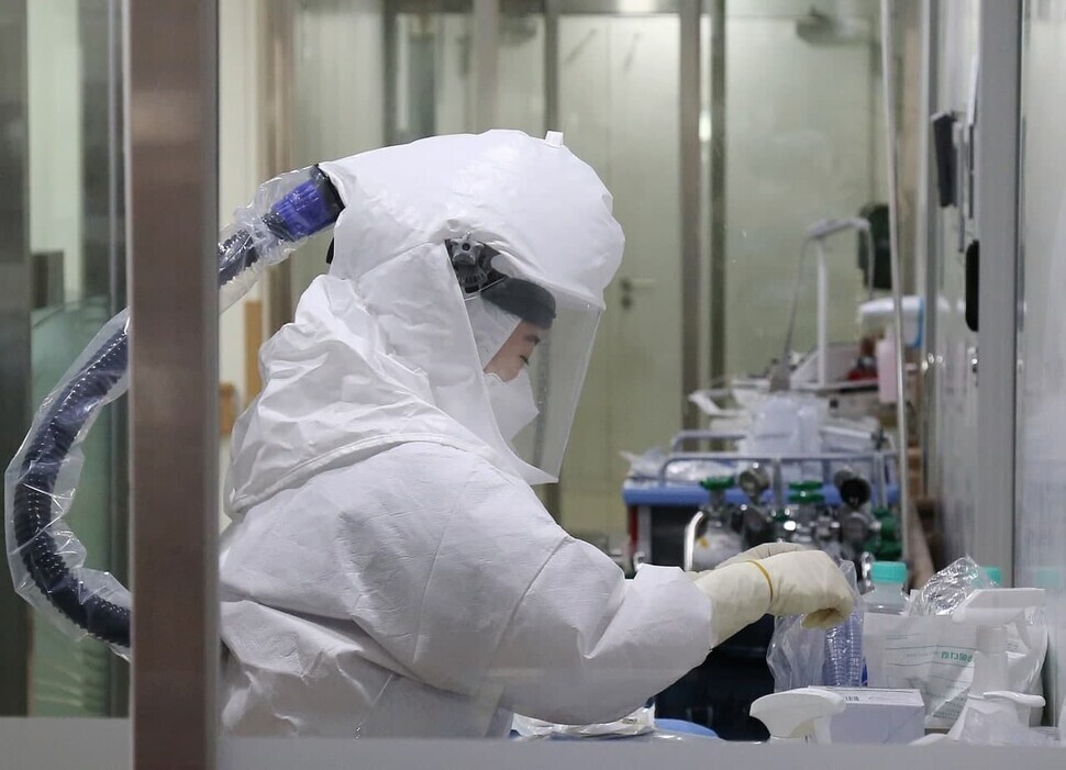 A nurse at Gachon University Gil Medical Center in Incheon’s Namdong District organizes a COVID-19 patient’s belongings while donning a Level D protective suit on Tuesday. (Yonhap News)