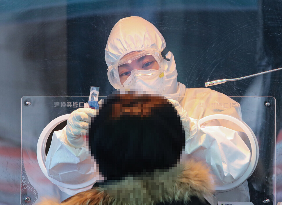 A medical worker takes a sample at a screening center in Seoul on Jan. 14. (Yonhap News)