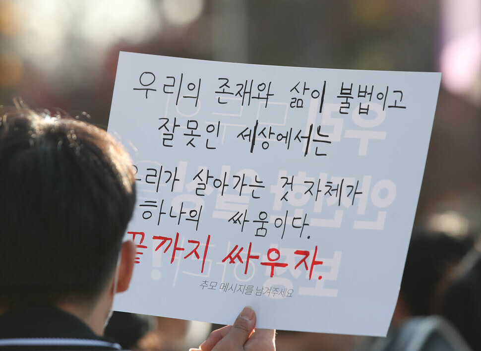 A person holds up a sign at the rally reading “In a world where our existence and lives are considered illegal and wrong, being alive is an act of resistance. Let’s resist to the end.”