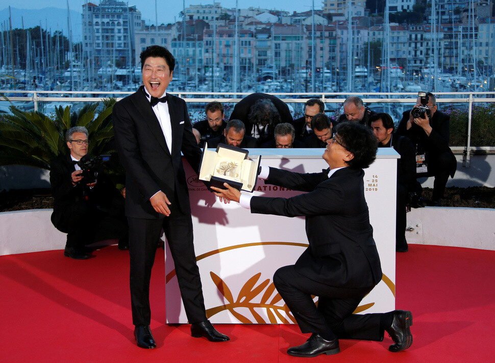 South Korean filmmaker Bong Joon-ho (right) offers his Palme d’Or prize to actor Song Kang-ho at the Cannes Film Festival on May 25. (Yonhap News)