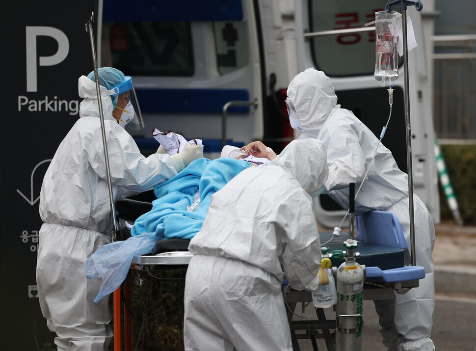 Healthcare workers transfer a confirmed COVID-19 patient to a hospital bed at the Seoul Medical Center on March 14. (Yonhap News)