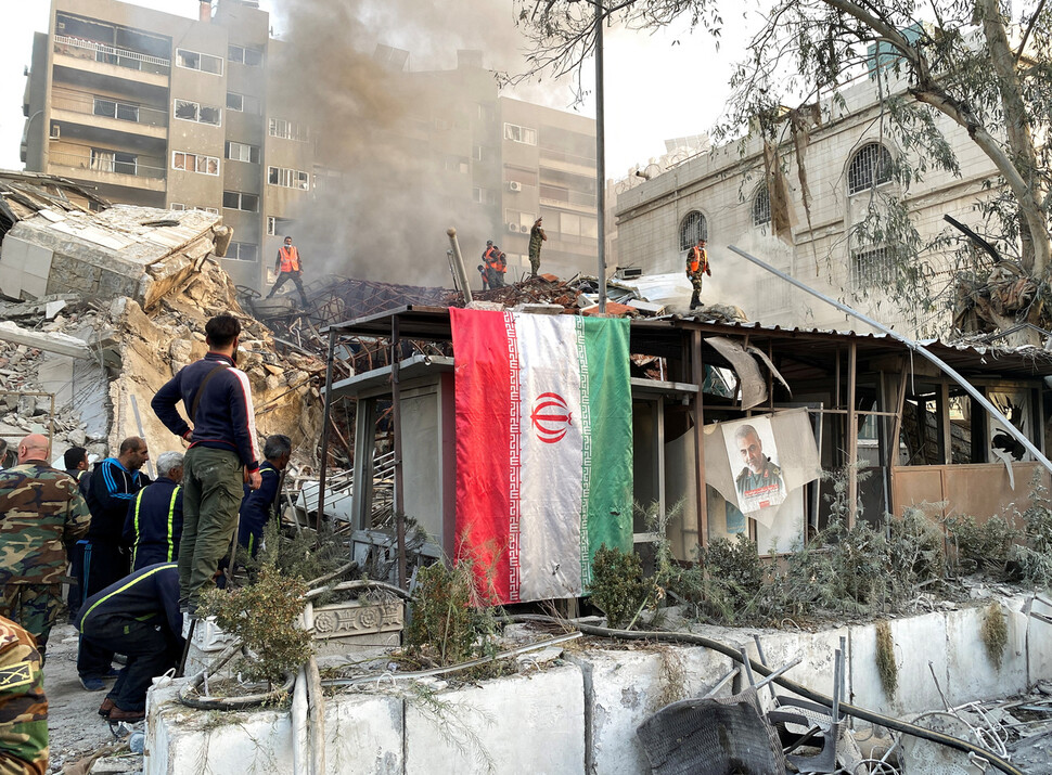 2024년 4월1일 시리아 수도 다마스쿠스에 자리한 이란 총영사관 건물이 이스라엘군의 공습으로 무너져 내렸다. 건물 잔해 앞에 찢긴 이란 국기가 걸려 있다. REUTERS