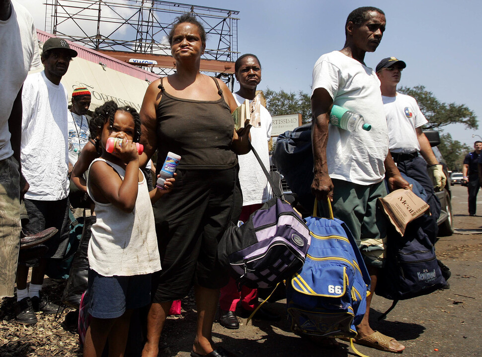 2005년 9월6일 뉴올리언스에서 피난민들이 버스에 탑승하고 있다. 뉴올리언스 시장은 수면 위를 떠다니는 석유와 가스가 생명에 위협이 된다며, 허리케인 카트리나가 발생한 지 일주일이 지나서도 남아있는 주민들에게 도시를 떠날 것을 호소했다. 그러나 문제는 빈곤율이었다. 가난한 사람들은 자동차조차 없었을 뿐더러, 자신의 모든 것인 집을 남겨놓고 떠나기 쉽지 않았다. REUTERS