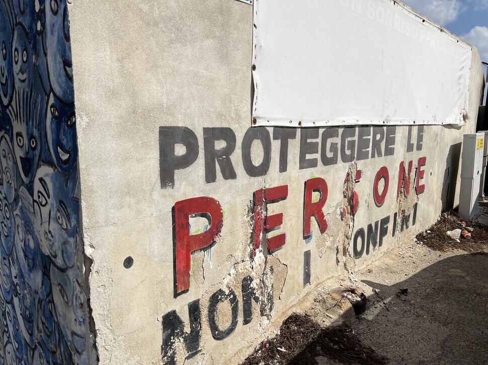 A wall at the Favaloro Pier on Lampedusa has graffiti that reads “proteggere le persone, non i confine,” or “protect people, not borders.” (Noh Ji-won/The Hankyoreh)