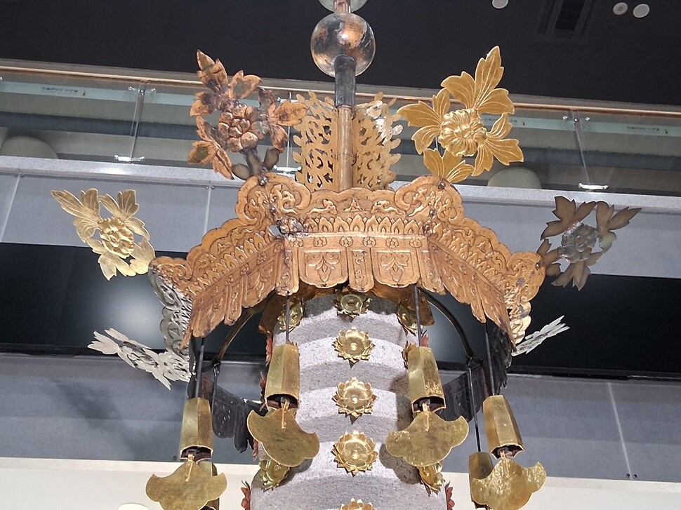 월정사 팔각구층석탑 맨 위 상륜부의 금속장엄물을 가까이서 본 모습. 겹쳐진 바퀴 모양 석조 보륜 위에 장식 꽃들이 튀어나온 팔각형의 구리판 덮개 장식물 보개와 그 아래 매달린 작은종(풍탁)들이 보인다. 보개 위로 불꽃 모양의 장식물 수연과 동그란 구 모양 보주가 보인다. 노형석 기자