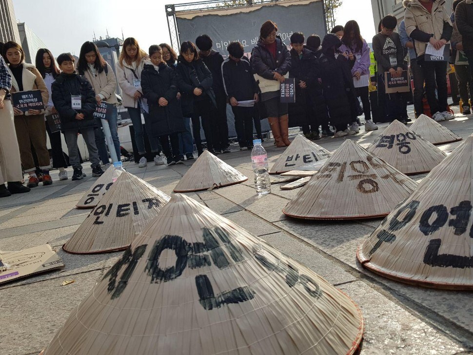 On Nov. 23, demonstrators in front of the Seoul Finance Center lay out traditional Vietnamese hats that display the names of victims of civilian massacres by South Korean soldiers during the Vietnam War.