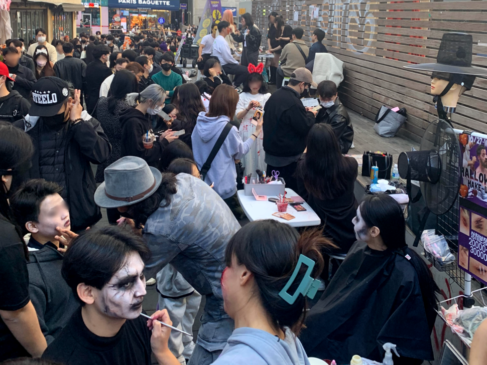 Revelers in Itaewon wait in line to have their faces painted by roadside shops set up in the neighborhood on Oct. 29. (courtesy of the author)
