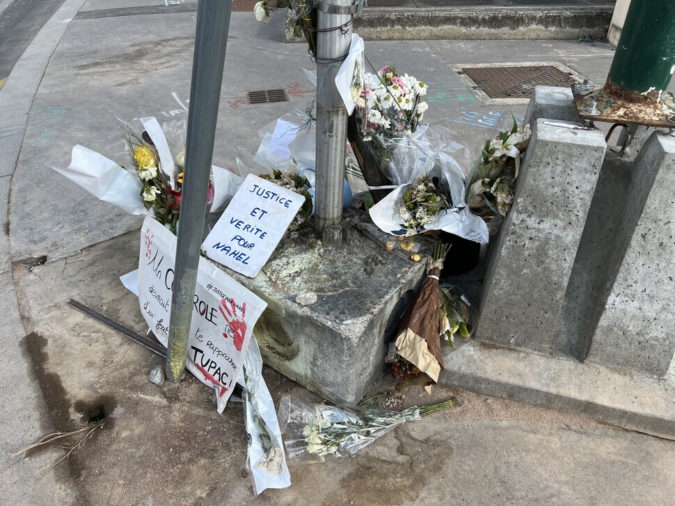 Flowers and written messages fill the spot where police shot and killed Nahel Merzouk on June 27 in Nanterre, France. (Noh Ji-won/The Hankyoreh)