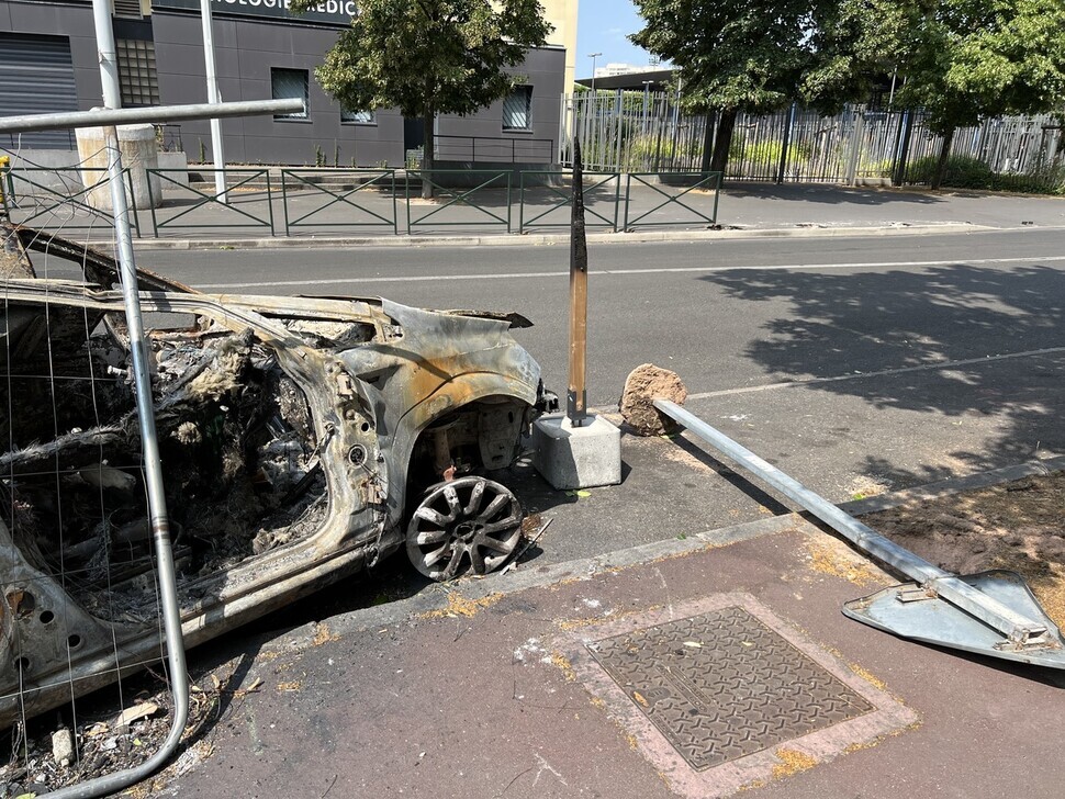 The remains of a torched car and uprooted signposts still litter the streets of Nanterre on July 3. (Noh Ji-won/The Hankyoreh)