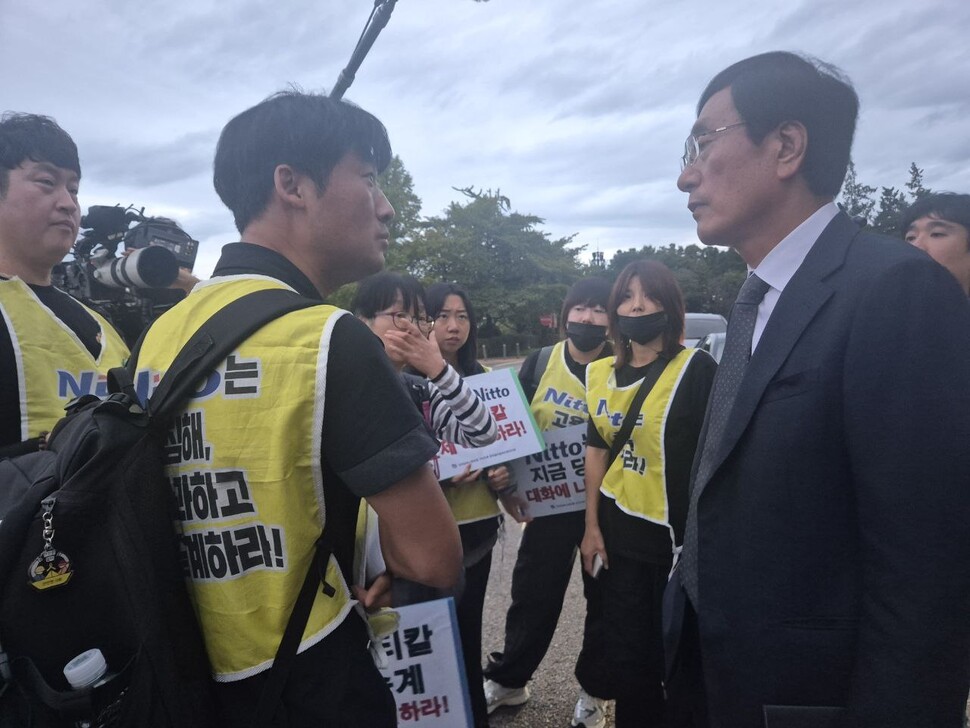 2025년 10월15일 국회 기후정의환경노동위원회 국정감사에 참고인으로 출석한 최현환(왼쪽) 금속노조 한국옵티칼하이테크지회 지회장이 증인으로 출석한 이배원(오른쪽) 니토옵티칼 대표이사에게 평택 공장과 구미 공장 간 인적 교류 사례를 설명하며 결단을 촉구하고 있다. 신다은 기자