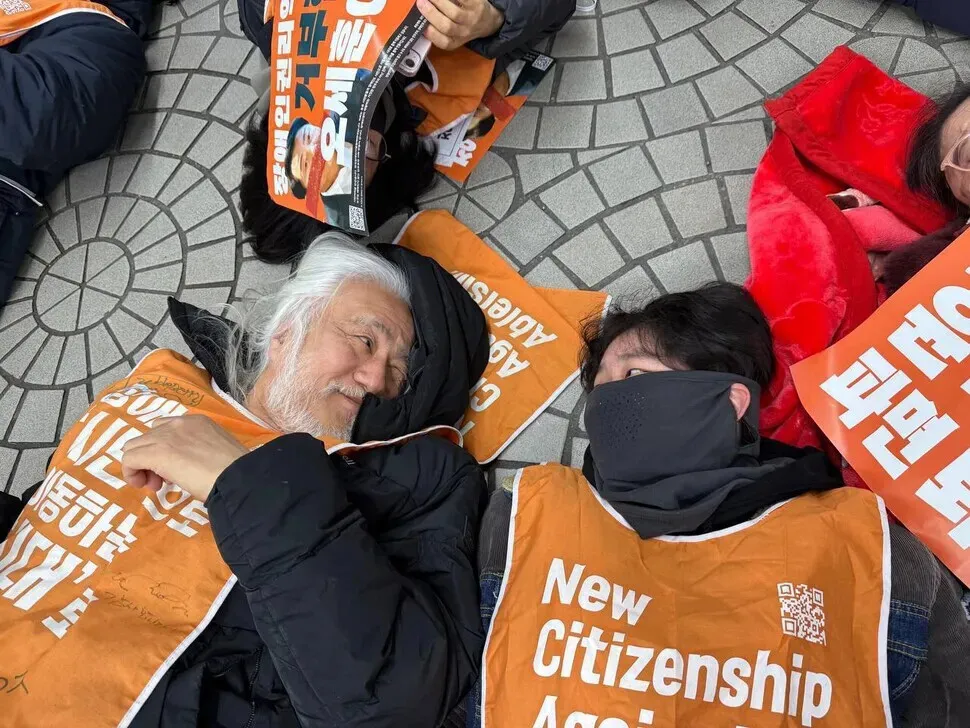 Moon Ga-bin (right) looks at disability activist Park Kyung-seok during a “die-in” protest by Solidarity Against Disability Discrimination. (courtesy of Moon)