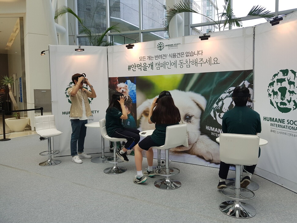 Viewers experience the virtual reality video being shown at Times Square on the morning of July 14 in the Yeongdeungpo District of Seoul shows the experience of dogs that will live and die in the raised cages of dog farmers. (by Lim Se-yeon
