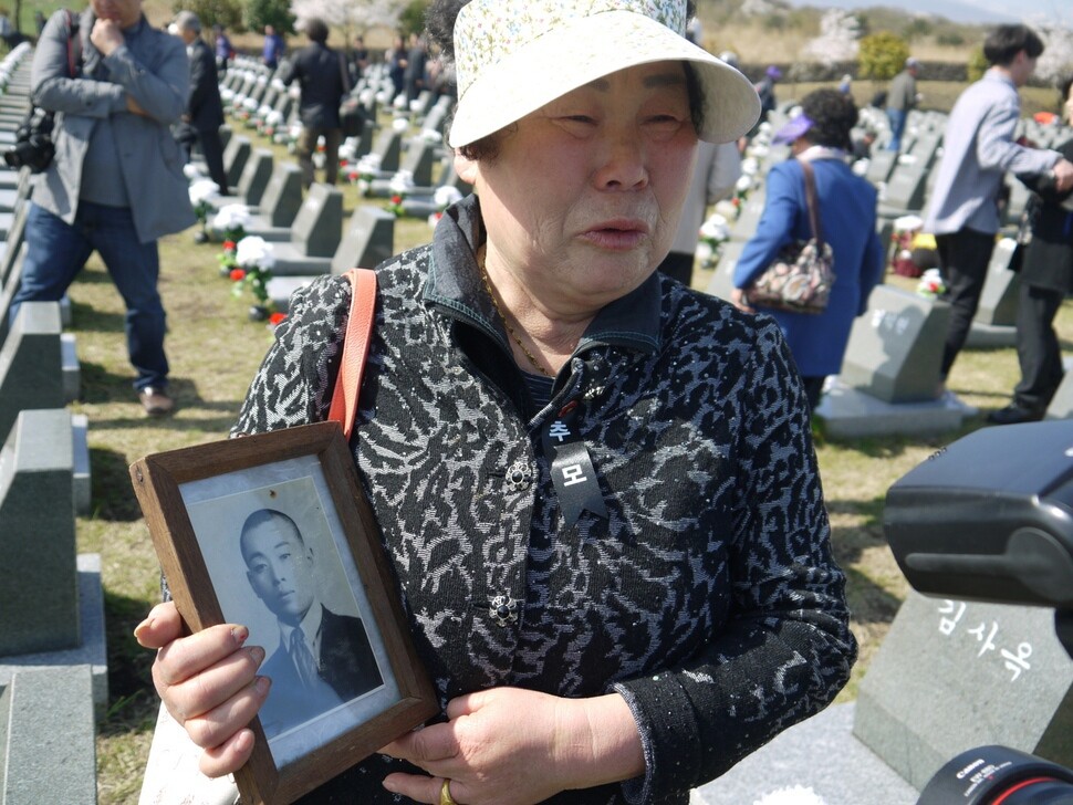Kim Yeong-ja weeps while holding a portrait of her father who was killed in the Jeju Uprising. Kim was looking for his headstone at the Apr. 3 Peace Park