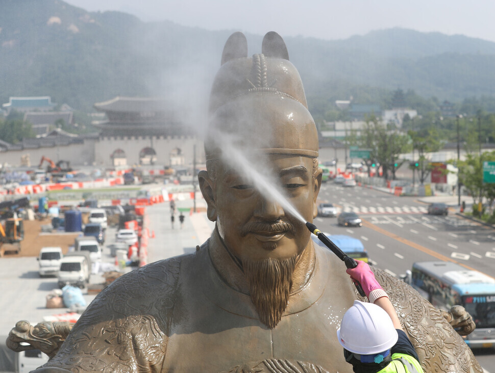 A city worker hoses down the statue of King Sejong the Great that sits in Gwanghwamun Square in downtown Seoul on July 18. (pool photo)