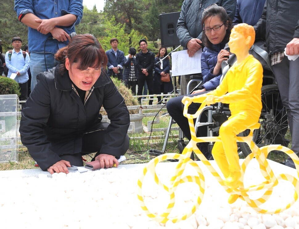 Kim Mi-suk, the mother of the late Kim Yong-gyun, weeps after a memorial statue of her son riding his bicycle is unveiled on April 28, 2019, in Namyangju, Gyeonggi Province, at a ceremony for unveiling the young worker’s grave. (Baek So-ah/The Hankyoreh)