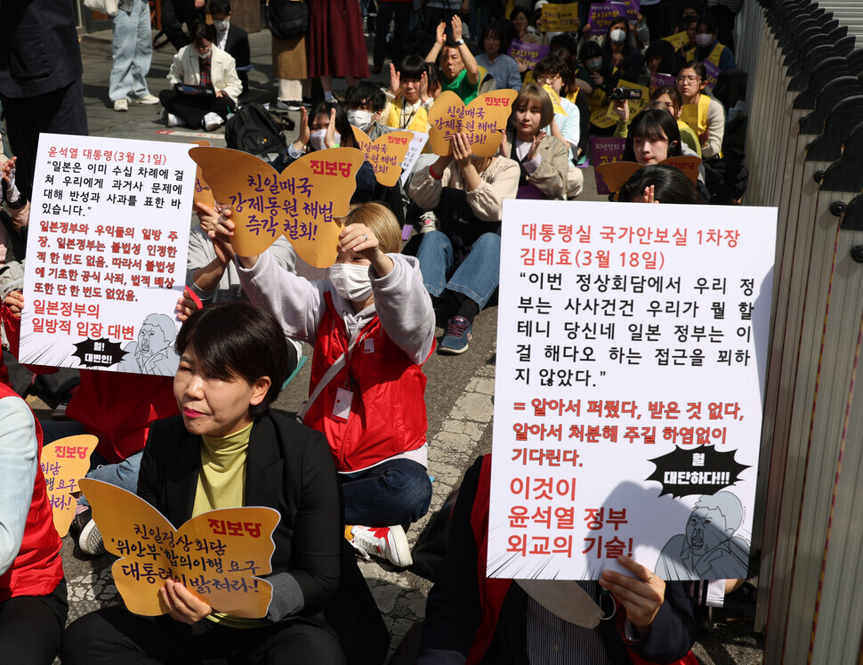 Participants at the 1,588th Wednesday Demonstration on March 22 hold up signs calling for the Yoon administration’s plan for compensating former forced laborers to be withdrawn. (Kang Chang-kwang/The Hankyoreh)