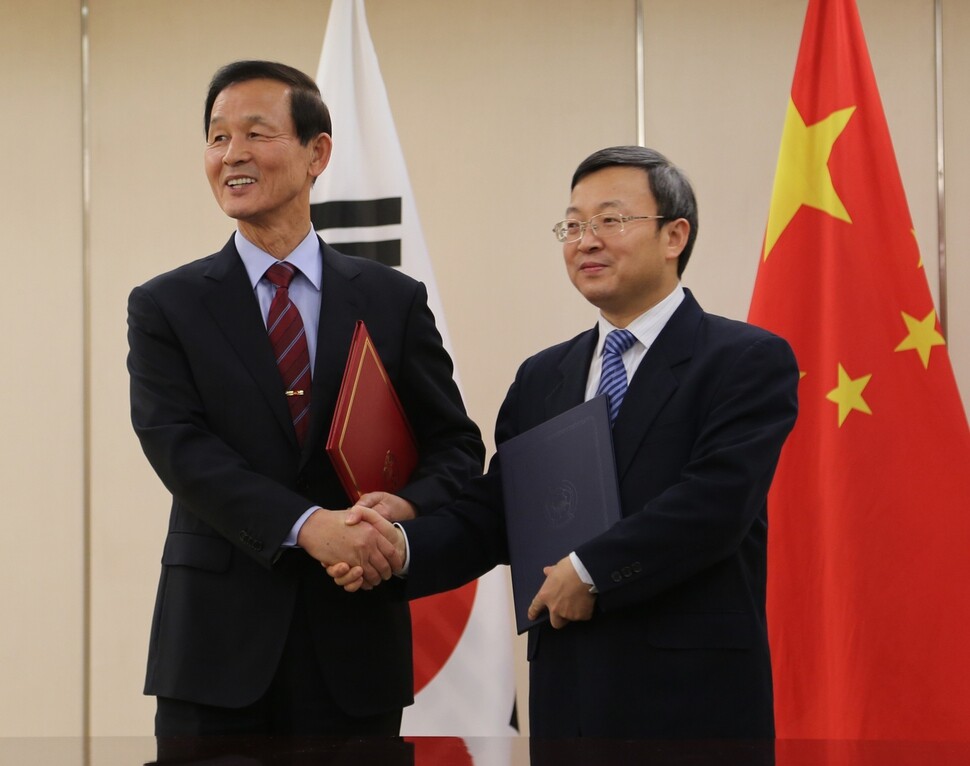 Then-South Korean Ambassador to China Kim Jang-soo and Chinese Vice Minister of Commerce Wang Shouwen shake hands following the conclusion of negotiations for the South Korea-China FTA in December 2015. (Yonhap News)
