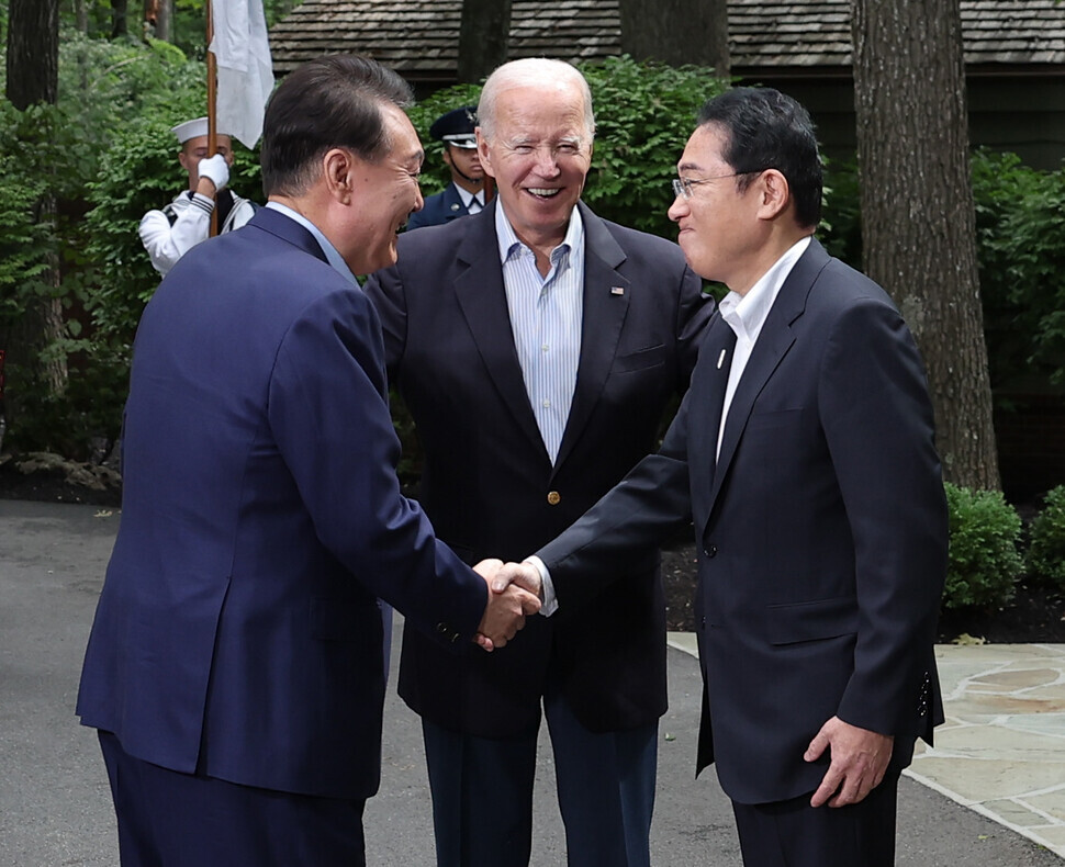 South Korean President Yoon Suk-yeol shakes hands with Japanese Prime Minister Fumio Kishida as US President Joe Biden smiles ahead of the three leaders’ summit at Camp David in Maryland on Aug. 18. (pool photo)