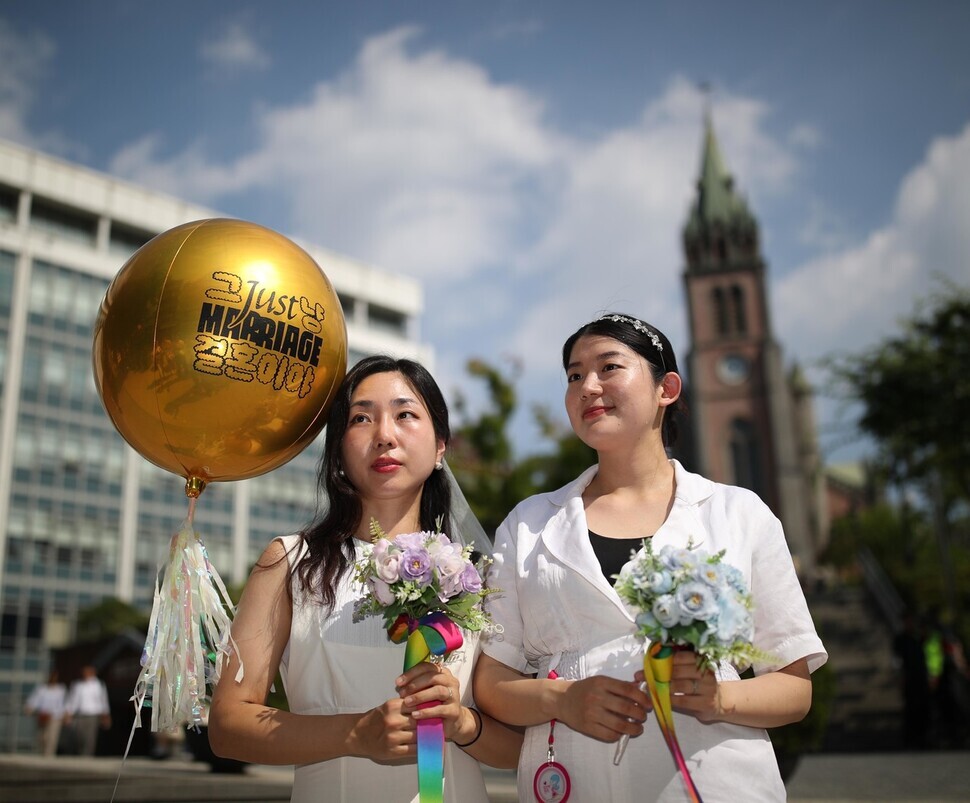 Kim Se-yeon and Kim Kyu-jin pose for wedding photos outside of Myeongdong Cathedral on July 1, the day of Pride. The couple had hoped to have their wedding there last November but was unable to. During the Pride event, the Kims announced that they were expecting a child together. (Kim Bong-gyu/The Hankyoreh)