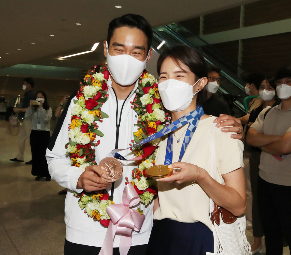 펜싱 국가대표 김정환(왼쪽)이 7월29일 인천국제공항 제2여객터미널을 통해 귀국해 아내의 목에 메달 두개를 걸어주고 있다. 작년 9월 결혼한 김정환은 〈한겨레〉와 인터뷰에서 “아내에게 올림픽에서 최선을 다하는 모습을 보여주 고 싶었다. 가장으로서 어떤 역경도 이겨낼 의지가 있다는 믿음을 심어주려고 더 열심히 했다”고 밝혔다. 연합뉴스