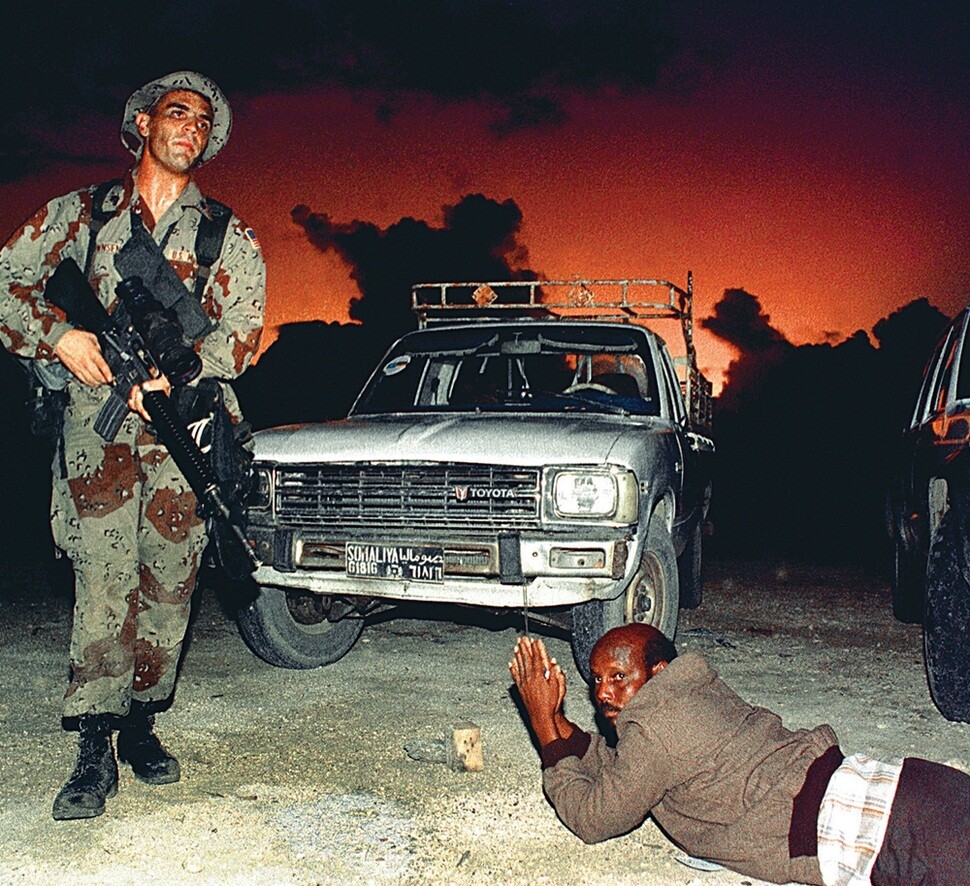 소말리아의 한 운전기사가 1992년 12월9일 소말리아 모가디슈 항구에서 미국 해병이 ‘희망 회복 작전’이란 상륙작전을 펼치는 동안 보안검색을 받느라 엎드려 있다.