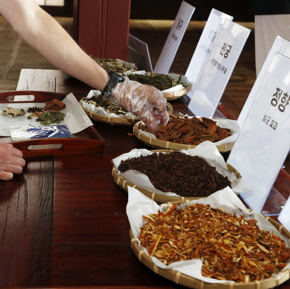 Participants in the “Changdeok Palace Pharmacy” program on Monday at the 7th Royal Culture Festival make herb pouches with herbs used in Oriental medicine. (Kim Hye-yun/The Hankyoreh)